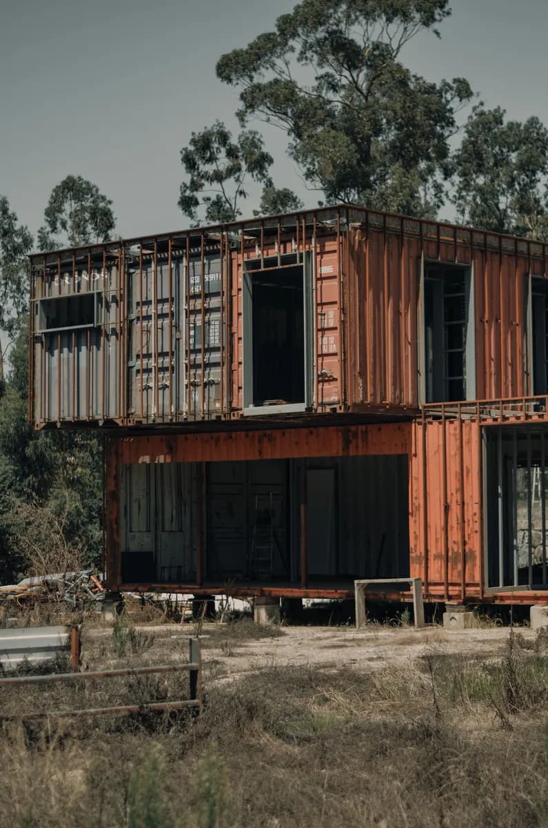 BookNoFees Beispielbild: Zweistöckiges Containerhaus mit großen Fenstern zwischen Bäumen
