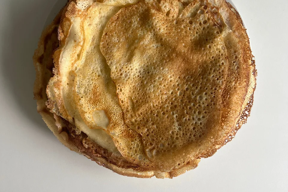 BookNoFees: Beispielfoto: Dünne, goldbraune Pfannkuchen auf einem weißen Teller
