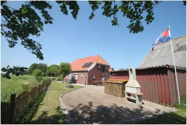 BookNoFees: Ferienwohnung in Dornum – Innenhof mit Backsteinhaus, Holzschuppen, Außenkamin und Fahnenmast