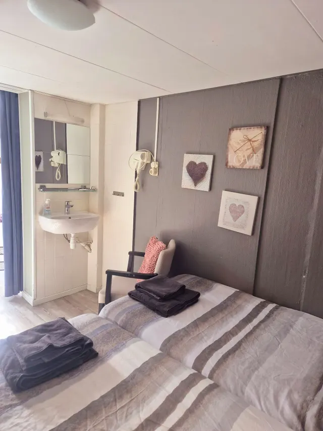 BookNoFees: Ferienwohnung in Domburg, Zeeland, Niederlande – Schlafzimmer mit gestreifter Bettwäsche, Wanddekoration und einem sichtbaren Waschbeckenbereich im eigenen Bad