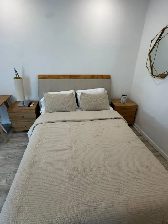 BookNoFees: Ferienwohnung in Cutler Bay – Schlafzimmer mit Doppelbett, Nachttischen aus Holz und einem geometrischen Wandspiegel