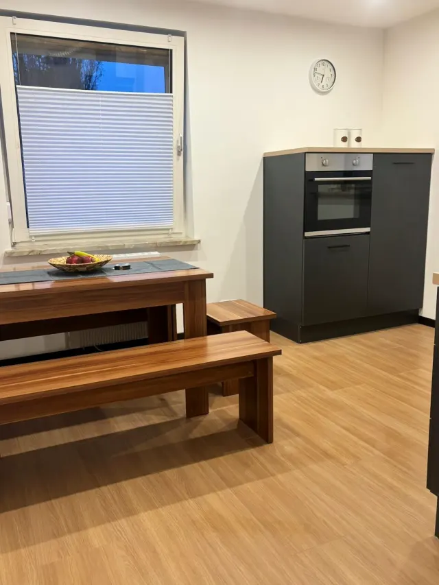 BookNoFees: Ferienwohnung in Bodenwerder – Küche mit Esstisch aus Holz, Sitzbank, Herd und Fenster mit Jalousie