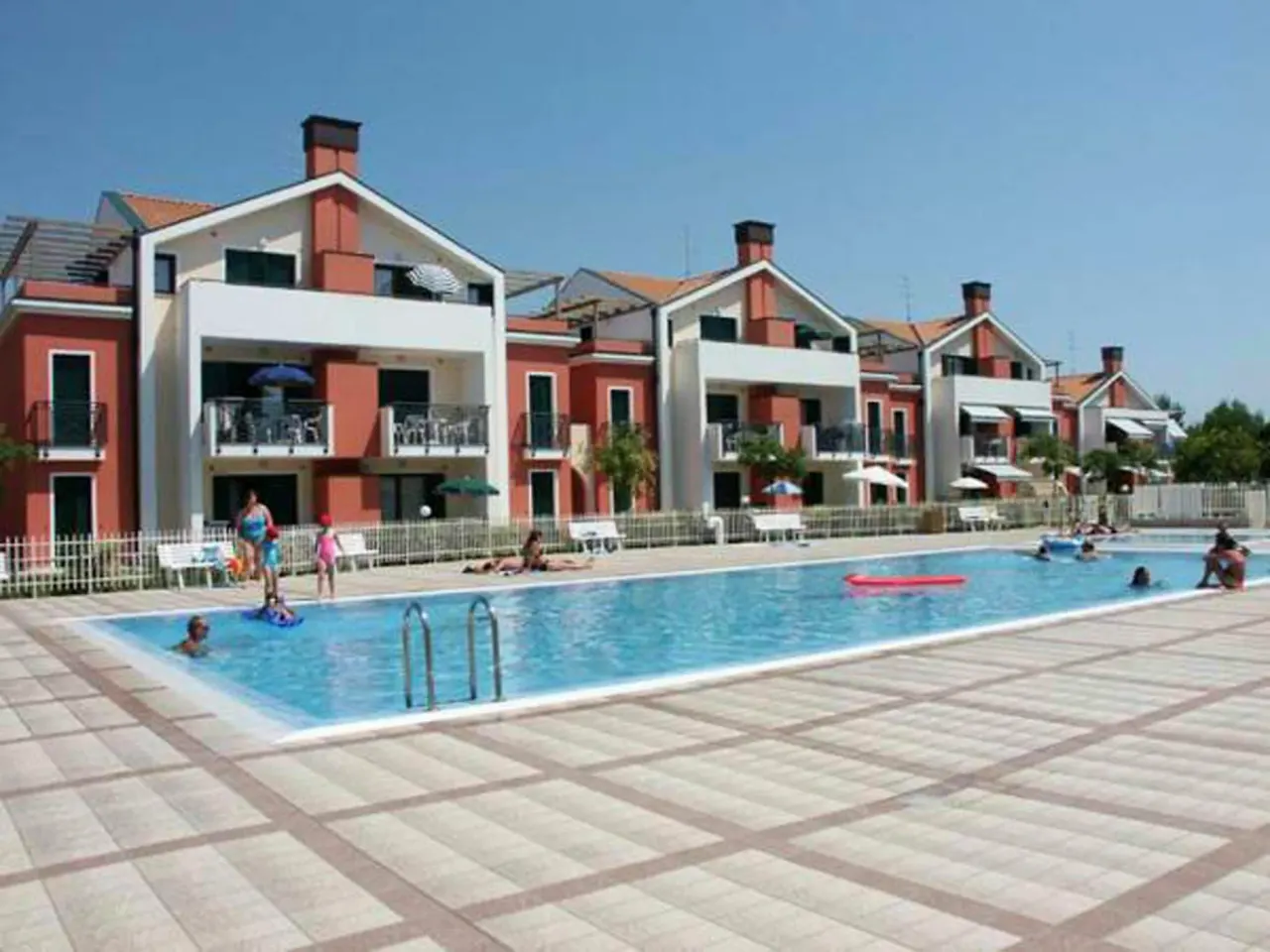 BookNoFees: Ferienwohnung in Cavallino-Treporti, Italien – Eine Gruppe von Menschen in einem Schwimmbad neben den Gebäuden des „Sunny Apartment On The Sea“ in Cavallino-Treporti