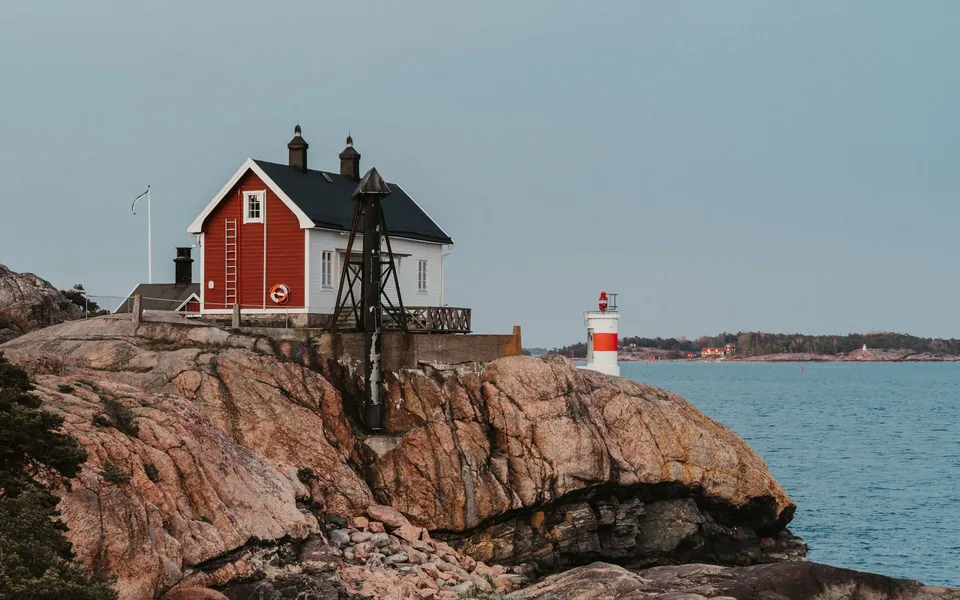 Rotes Haus und Leuchtturm an Schwedens Felsenküste
