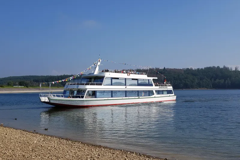 Das Ausflugsboot MS Sorpesee auf dem See bei Sundern, mit Wald am gegenüberliegenden Ufer